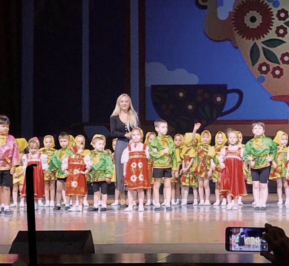 Tatiana Samoshkina on stage with young dancers in Russian folk costumes at the Moskvich Cultural Centre