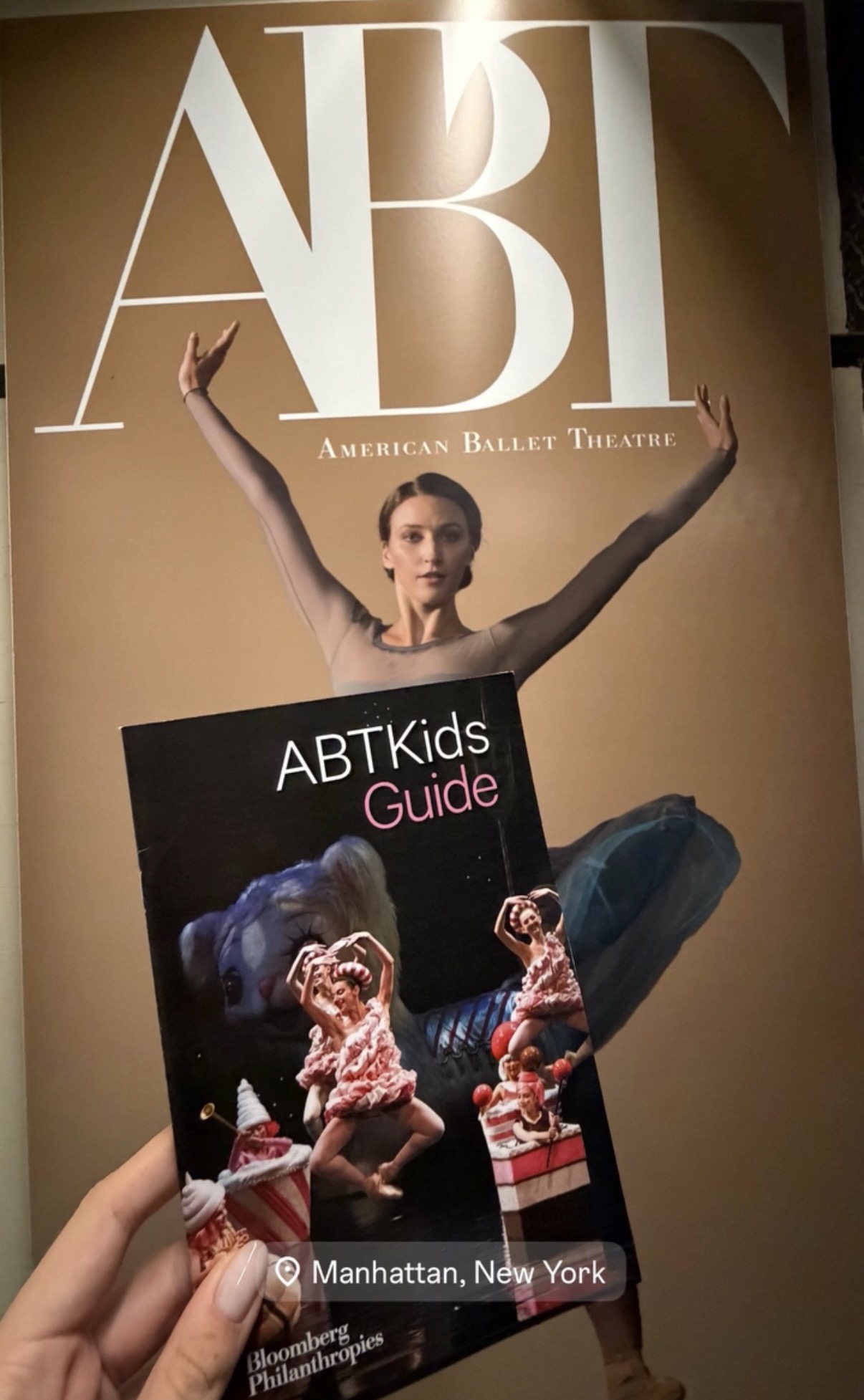 ABTKids Guide held up in front of an American Ballet Theatre poster
